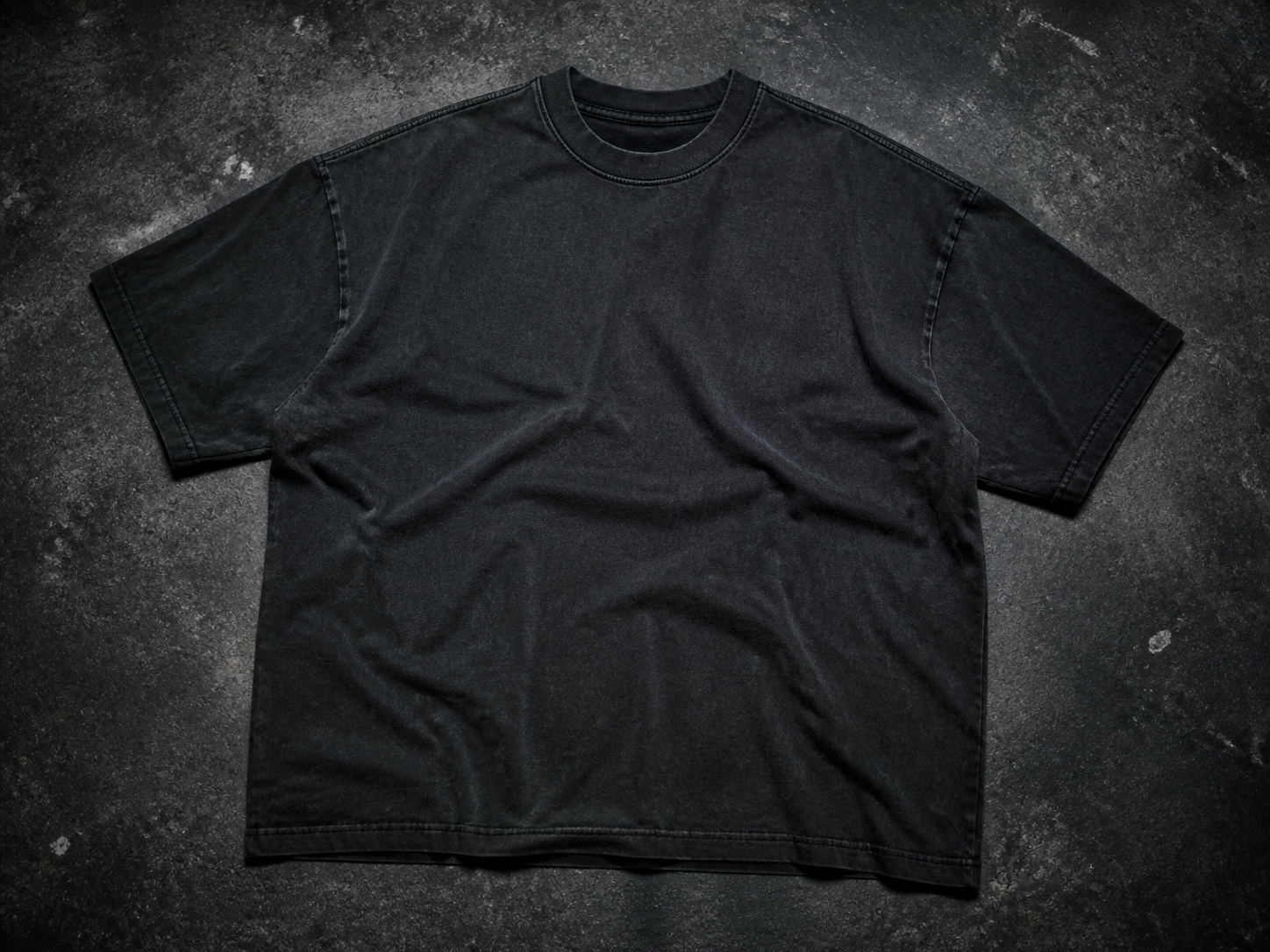 Washed black Progress Tee laid on a charcoal concrete surface