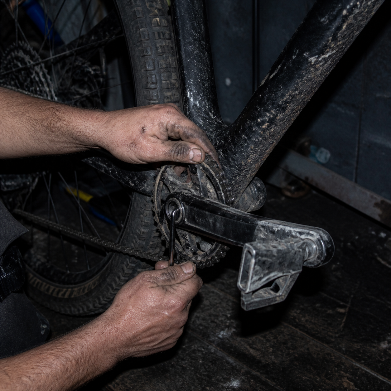 Mud-streaked hands working on a mountain bike drivetrain